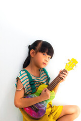 Cute little girl playing ukulele on white background