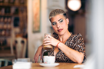 A interesting hipster woman looks sideways with a glass in a bar