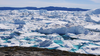 Icebergs in turquoise water close to coast at Ilulissat, Greenland