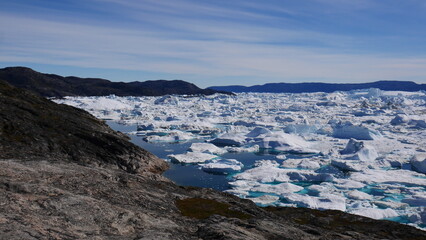 Fototapeta na wymiar Icebergs in the water close to coast at Ilulissat, Greenland