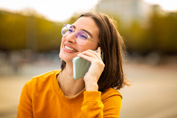 Happy young woman talking on cellphone outside