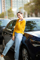 Happy young woman standing by her new car