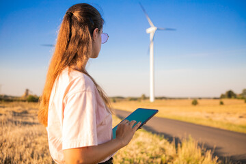 girl watching windmills and watching at tablets