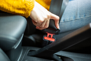 Woman driver hand fastening seatbelt in car