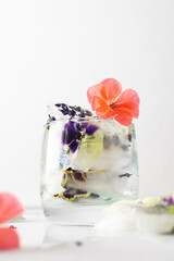 Refreshing cold drink with frozen flowers, colorful pansies and geraniums, lavender and Verbena
