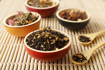 bowls of black tea on bamboo mats with spoons