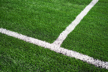 Green synthetic grass sports field with white line.
