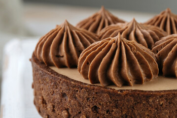 Mini chocolate cakes on wooden background. Chocolate cream rosettes on a cake.