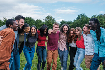 Group of young people of multiethnic origin together embracing and having fun outdoors