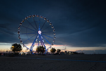 Italy, August 2022: view of the ferris wheel of Rimini with all the colored lights near the beach...
