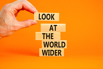 Look at the world wider symbol. Concept words Look at the world wider on wooden blocks on a beautiful orange background. Businessman hand. Business and look at the world wider concept. Copy space.