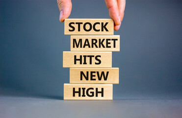 Stock market hits new high symbol. Concept words Stock market hits new high on wooden blocks on a beautiful grey background. Businessman hand. Business stock market hits new high concept. Copy space.