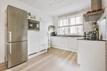 Interior of light kitchen and dining room with balcony doors in contemporary apartment at daytime