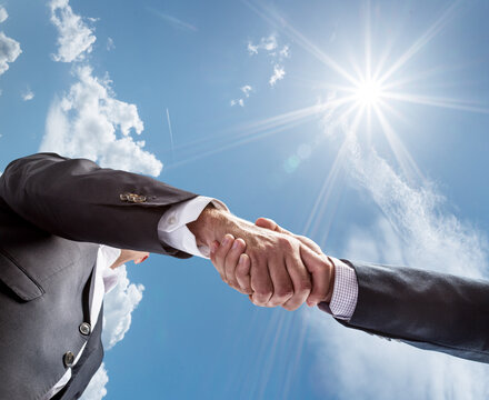 Business or political partnership concept. Close-up handshake against a blue sunny sky. Peace concept.
