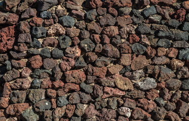 Wall built of lava remains or igneous rocks. Close-up.