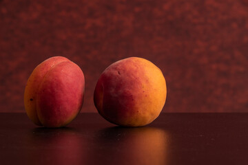 Fresh apricots on black table with red background