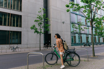full length of amazed young woman in summer outfit riding bicycle in berlin.