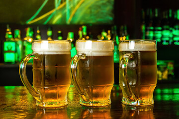 Close-up of three mugs of foamy beer on the bar