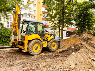 Fototapeta na wymiar bright, yellow excavator digs a hole in the sand. construction machinery. reliable vehicle for the construction of roads and pits. laying communications