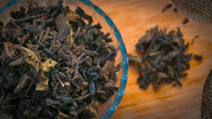 Fototapeta na wymiar Dried roasted green tea leaves on the bowl on burlap background, Japanese tea, Houji tea