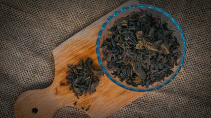 Dried roasted green tea leaves on the bowl on burlap background, Japanese tea, Houji tea