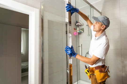 Workers are installing glass door of the shower enclosure