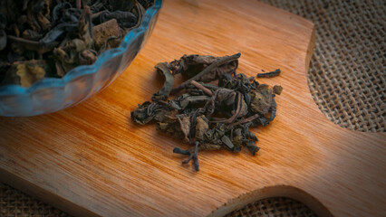 Dried roasted green tea leaves on the bowl on burlap background, Japanese tea, Houji tea