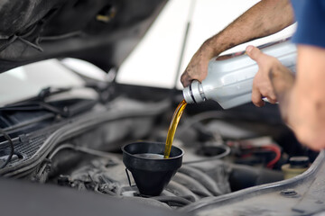 Obraz na płótnie Canvas Man auto mechanic repairs car in autoservice, station. Changes oil.