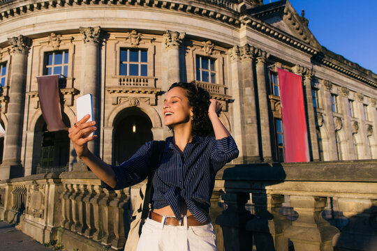 cheerful young tourist taking selfie near bode museum in berlin.