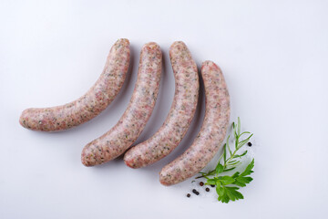 Raw coarse Allgäu bratwurst garnished with herb and spice offered as top view on a white board...