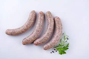 Raw coarse Allgäu bratwurst garnished with herb and spice offered as top view on a white board with text space