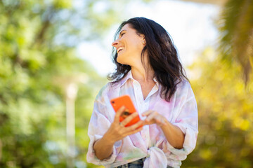Joyful woman using mobile phone at park