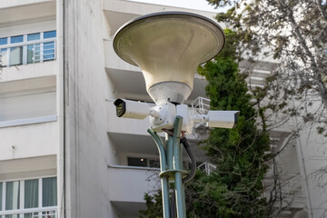Two side-by-side hanging CCTV cameras mounted on the corner of the building for the safety of residents.