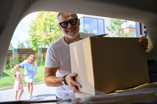 Man Takes Out Box From Trunk. View From Inside Car