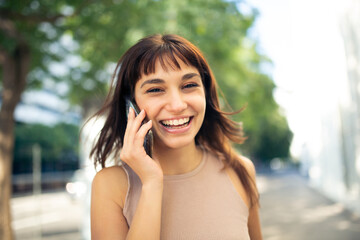 Cheerful young woman using cellphone outside in city