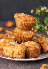 Homemade muffins with apricots and almonds on brown background