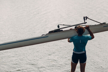 Sportsman single scull man rower carrying boat to competition © primipil