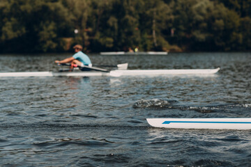 Sportsman single scull man rower rowing on boat.