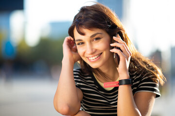 Beautiful young woman talking on mobile phone sitting outside