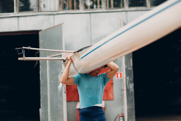 Sportsman single scull man rower carrying boat to competition © primipil