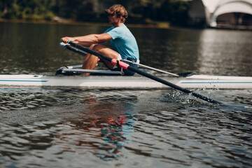 Sportsman single scull man rower rowing on boat.