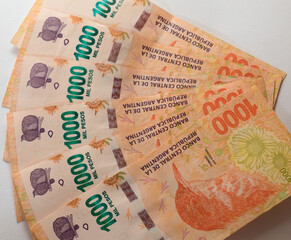 Billetes de 1000 pesos argentinos desplegados en abanico sobre fondo blanco