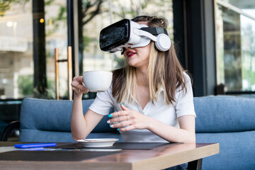 Cute blonde wearing VR set and drinking tea