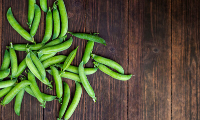 Pea pods on wooden background with space for text.