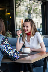 Cute lady sitting at the cafe and talking with her friend