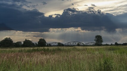 Burzowe chmury nad terenem zalewowym Wisły w okolicach kąpieliska Przylasek Rusiecki. W tle most...