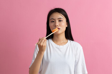 Asian beauty model girl eating Sushi roll, healthy japanese food. Beautiful woman holding chopsticks with Philadelfia roll.