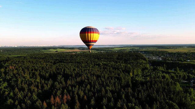 the balloon is gaining altitude, flying over the forest