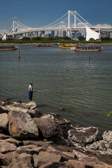 Fototapeta na wymiar Fisherman in Tokyo Bay with the Rainbow Bridge in the background 