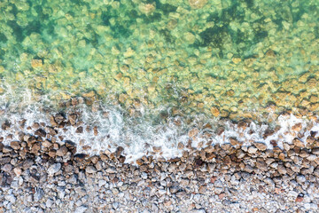 Texture of the beach with stones and turquoise water, paradise landscape, copy space.
